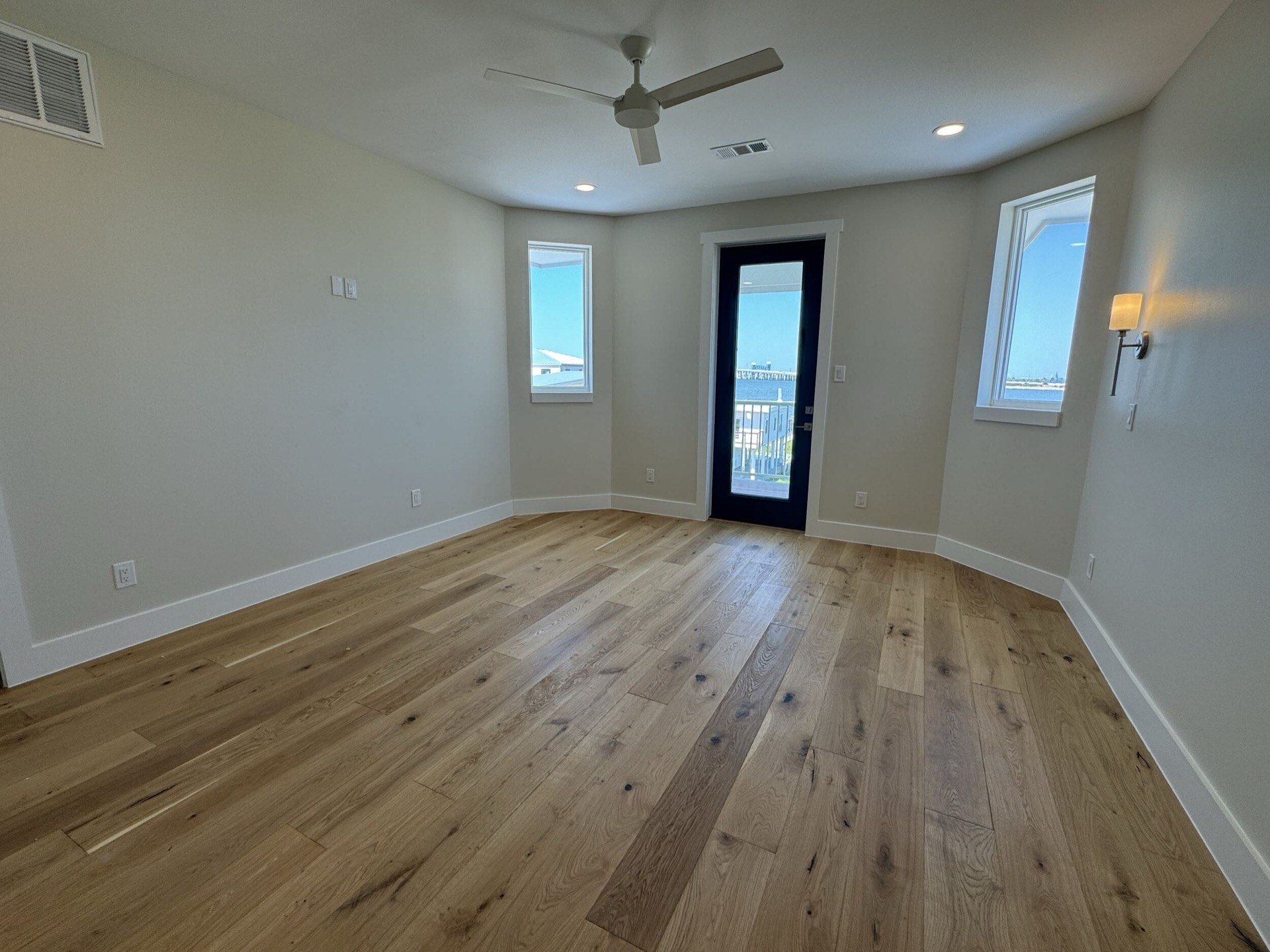 Bathroom featuring dark green vanity with marble countertop, dual brass wall-mount faucets, and decorative tile in the West Bay coastal home