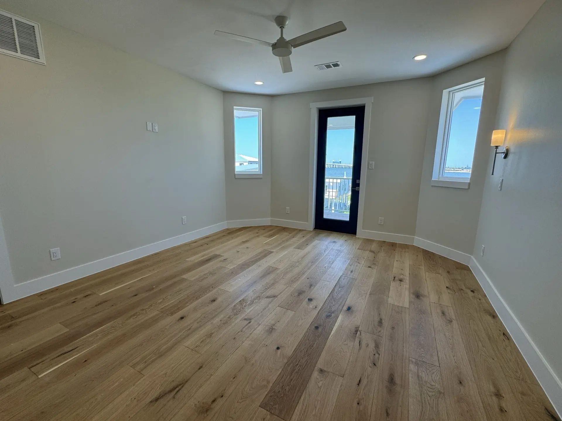 Bathroom featuring dark green vanity with marble countertop, dual brass wall-mount faucets, and decorative tile in the West Bay coastal home