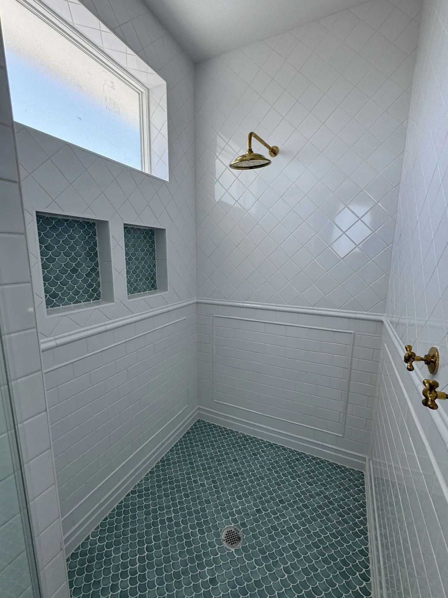 Brass wall-mount faucet detail above the dark green vanity with white marble countertop in the traditional coastal Craftsman bathroom