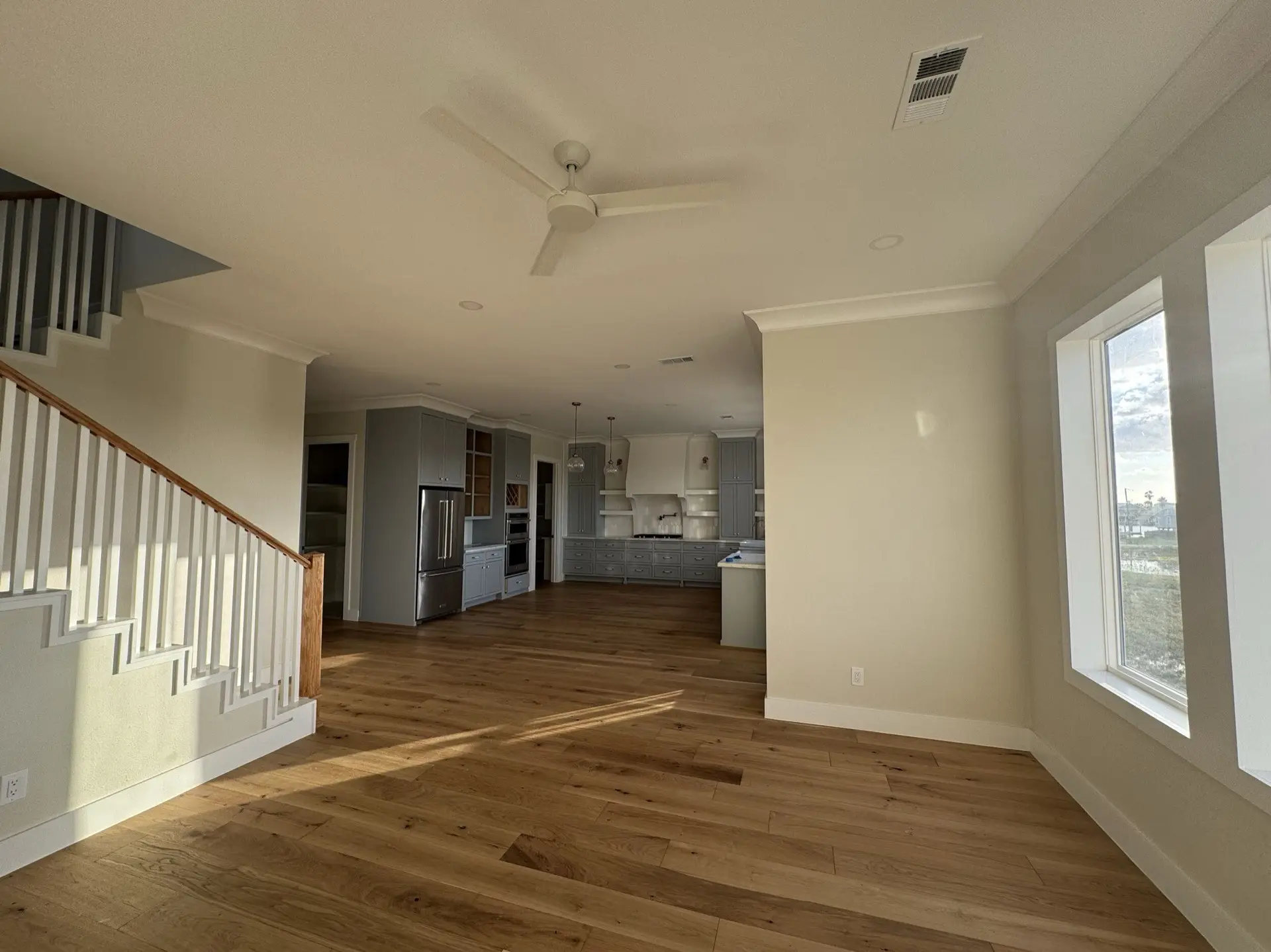 Third guest room or flex space with crown molding, oak floors, and ample window light in the West Bay coastal Craftsman home