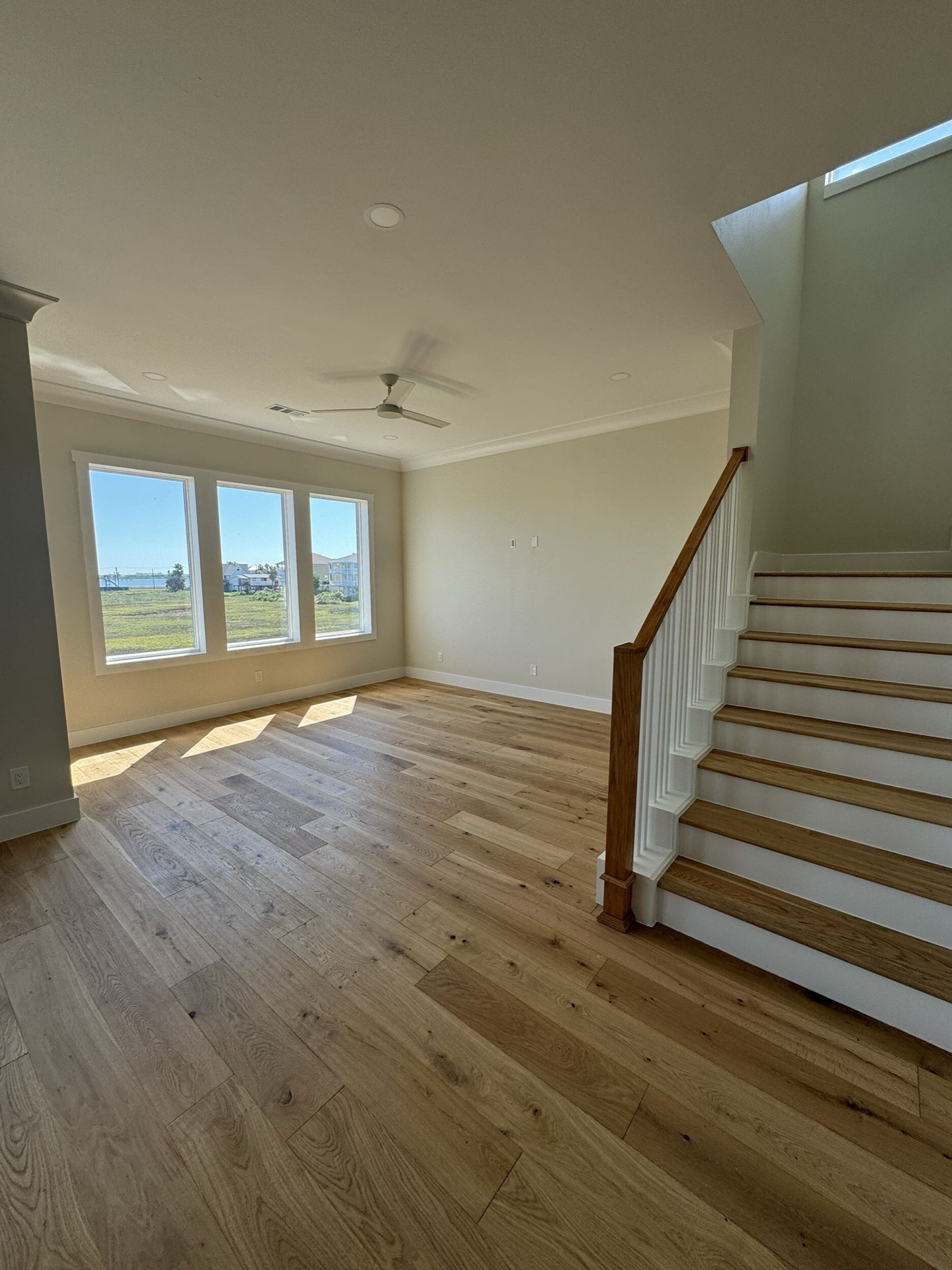Sunset panorama from the West Bay upper deck with golden light reflecting across the bay, bridge silhouette, and coastal marshland
