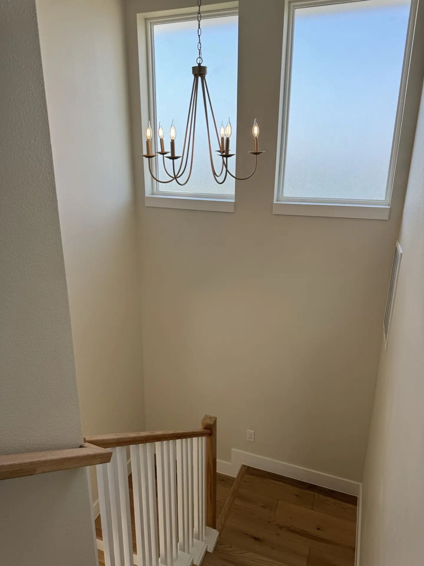 Dusk exterior of the West Bay coastal Craftsman with warm interior lighting illuminating the double-stacked porches against the bay sunset