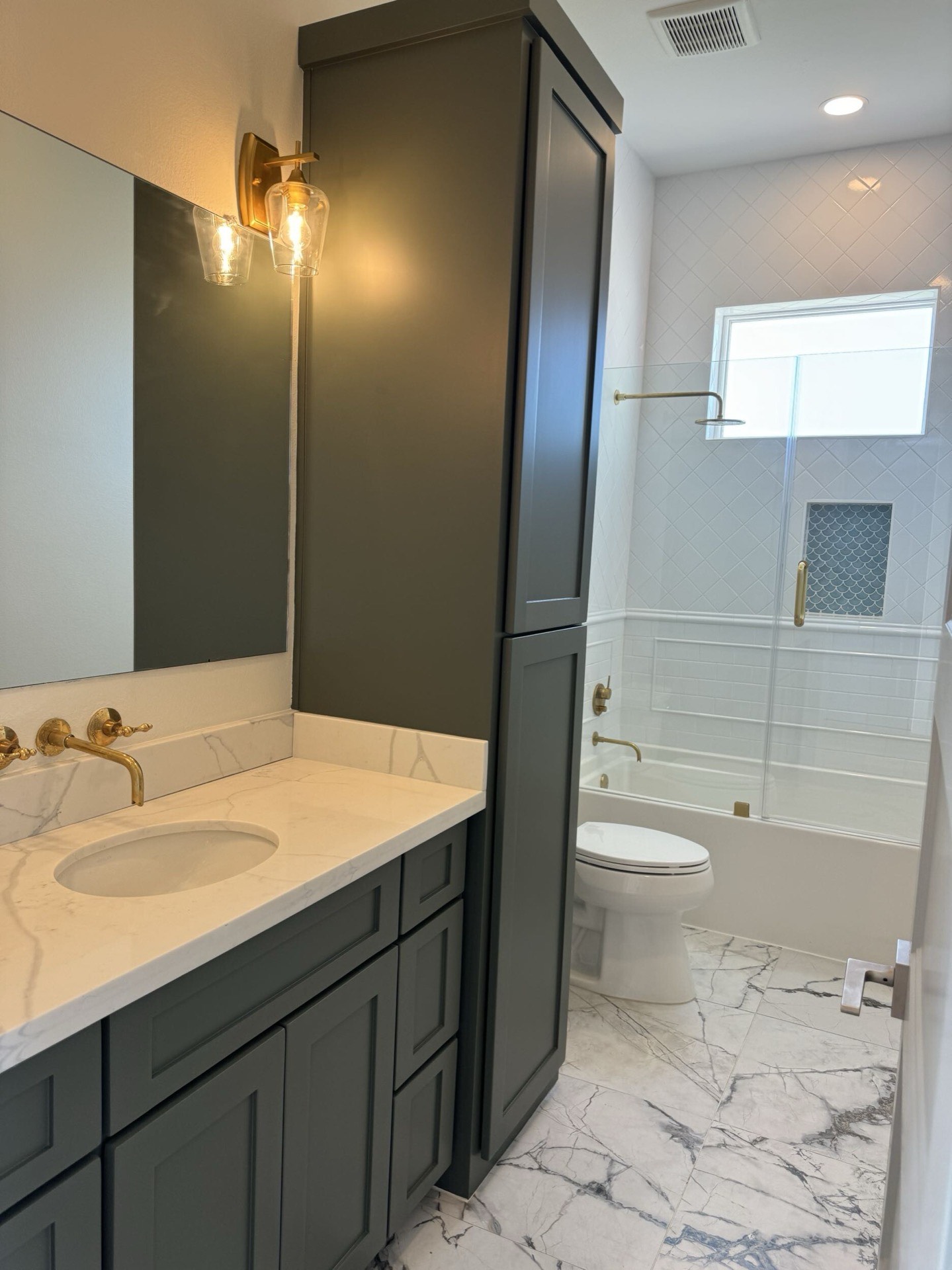Stainless steel double wall oven installation flanked by sage green pantry cabinetry with crown molding detail at the ceiling line