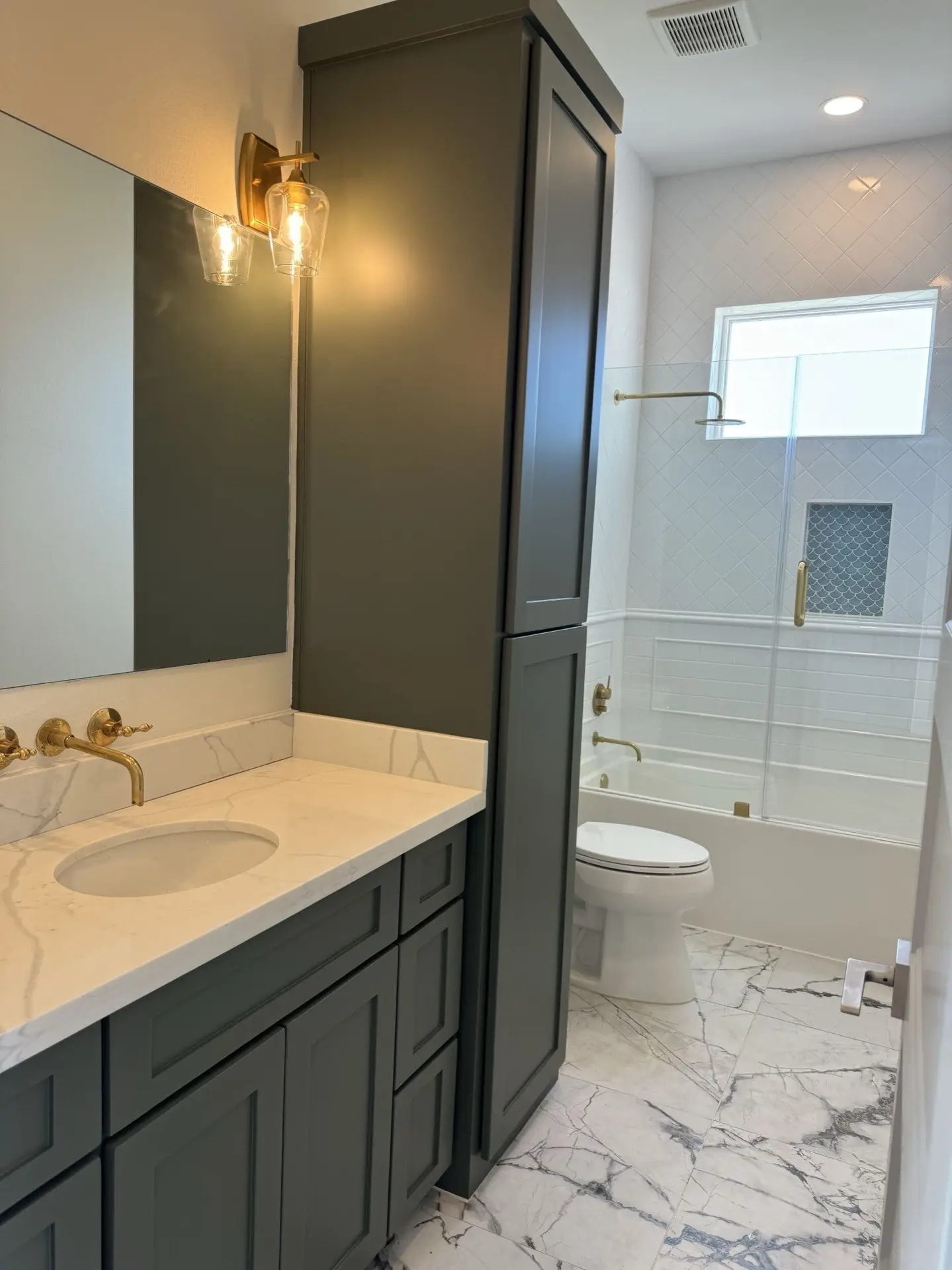 Stainless steel double wall oven installation flanked by sage green pantry cabinetry with crown molding detail at the ceiling line